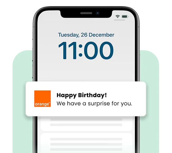A smartphone lock screen displaying the date “Tuesday, 26 December” and time “11:00” with a notification from Orange that reads, “Happy Birthday! We have a surprise for you.” The Orange logo appears to the left of the message.