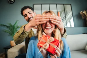 Happy woman receiving a surprise gift from a man, symbolizing how dopamine and oxytocin create joy, trust, and emotional engagement that strengthen brand loyalty.